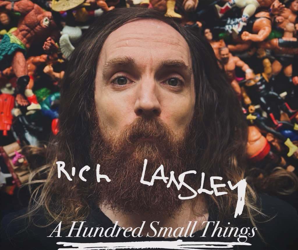 A photo of Rich Lansley's face, where he is lying on a pile of very small children's toys